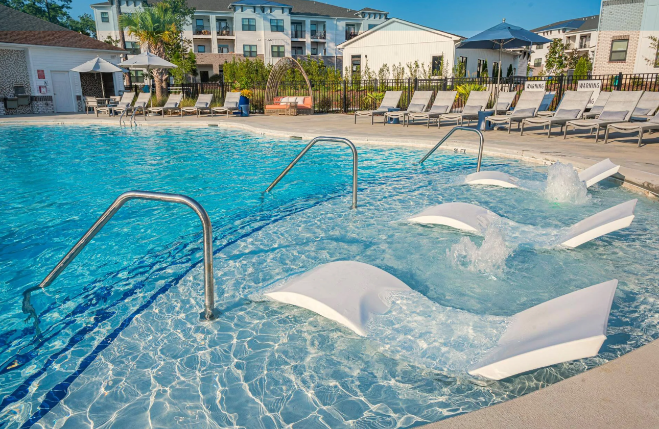 In-water loungers and sun shelf along the freeform pool edge.